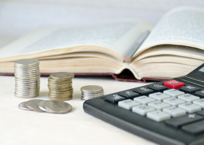 Coins stacked pile, calculator, open book light background. Calculation of financial stability and business development